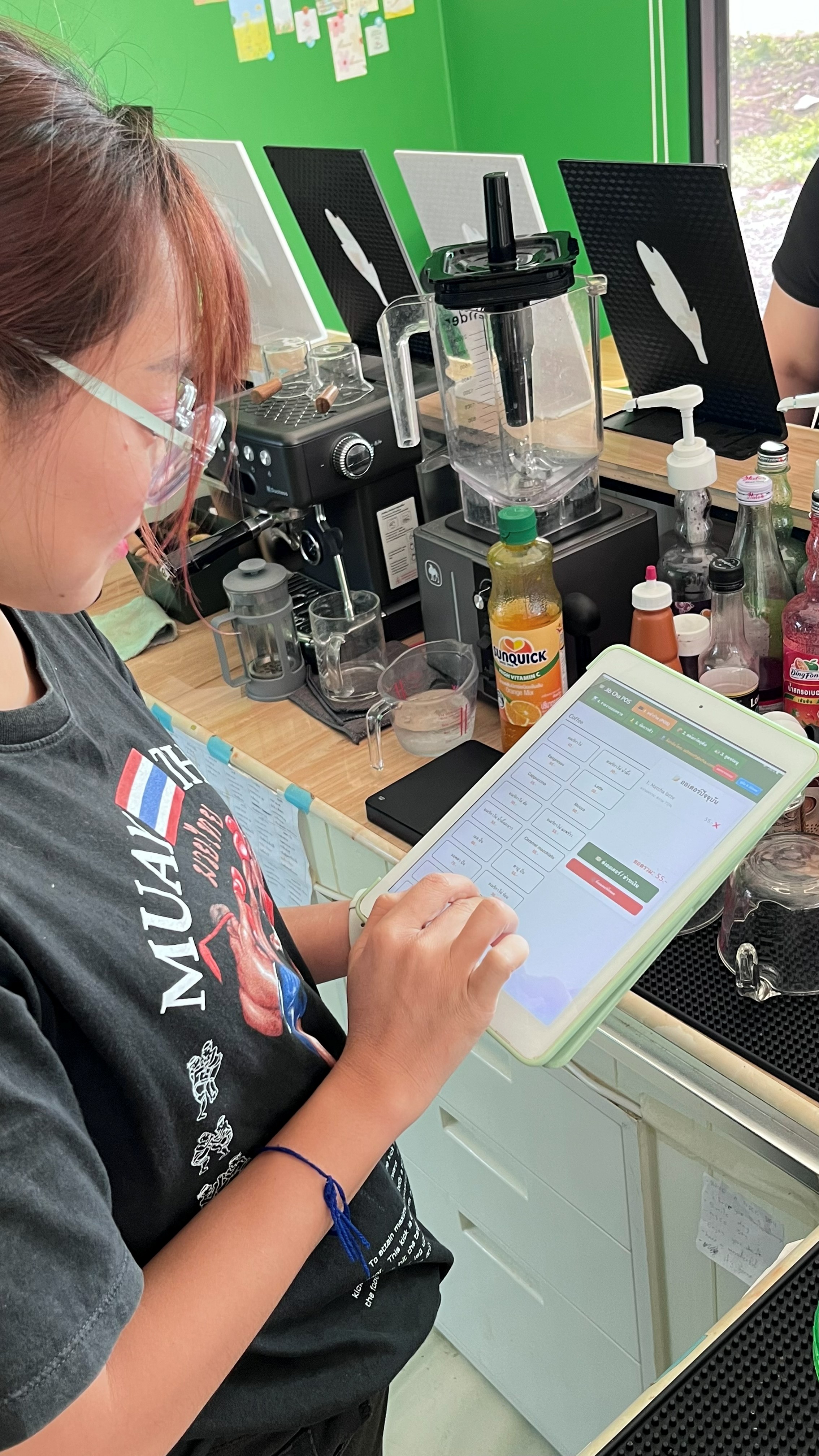 พนักงานร้านเครื่องดื่มถือแท็บเล็ตแสดงหน้าระบบ Custom POS